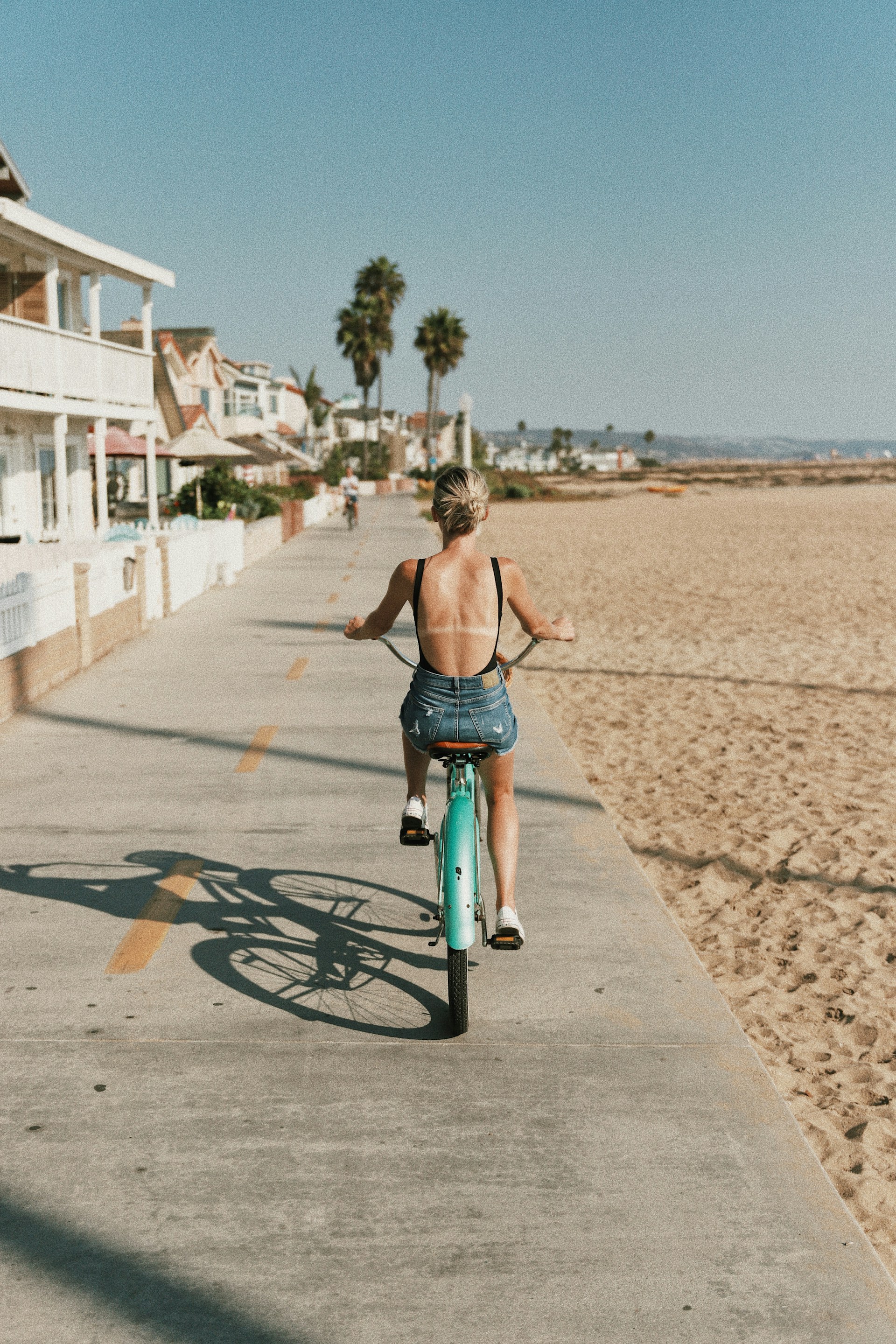 Woman riding a beach cruiser bike along the boardwalk
